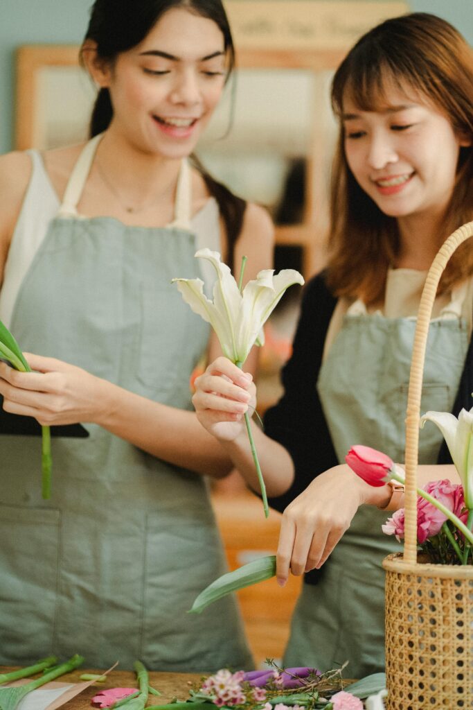 Crop content Asian colleagues interacting while working in flower shop